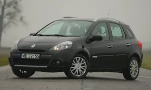 Ciemny Renault Clio 3 na mokrej drodze, widoczne przednie żarówki.