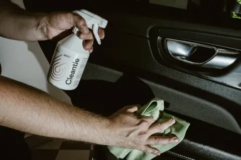 Ręce czyszczą wnętrze samochodu, używając zasadowego APC Cleantle i zielonej mikrofibry.