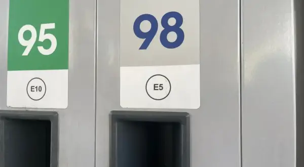 Dwa dystrybutory paliwa: jeden z zielonym oznaczeniem 95 E10, drugi z niebieskim 98 E5.