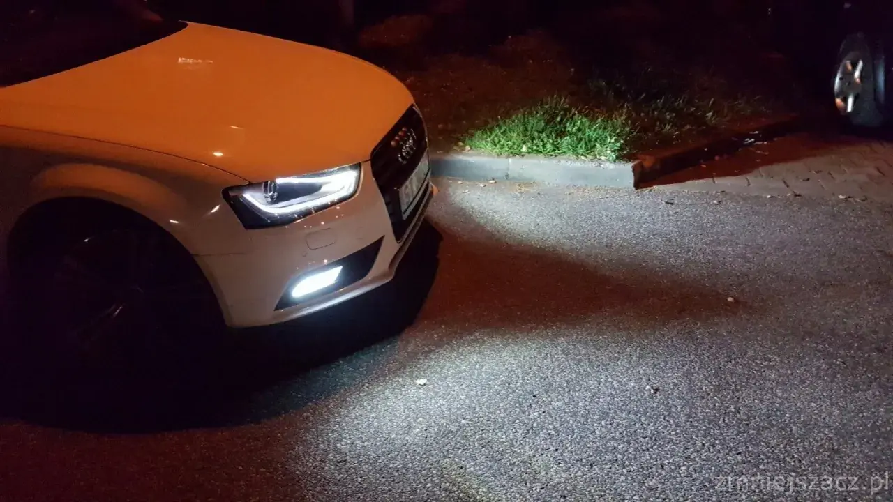 Białe Audi A4 B8 po lifcie z zapalonymi światłami przeciwmgielnymi. Wymiana żarówki przeciwmgielnej zakończona sukcesem.