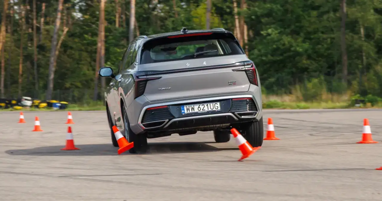 Szary SUV wykonuje test łosia, gwałtownie omijając pomarańczowe pachołki na torze.