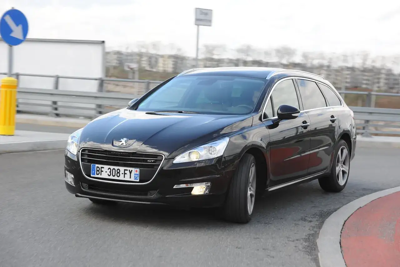 Czarny Peugeot 508 kombi na zakręcie. Wymiana żarówki przód w tym modelu jest prosta.