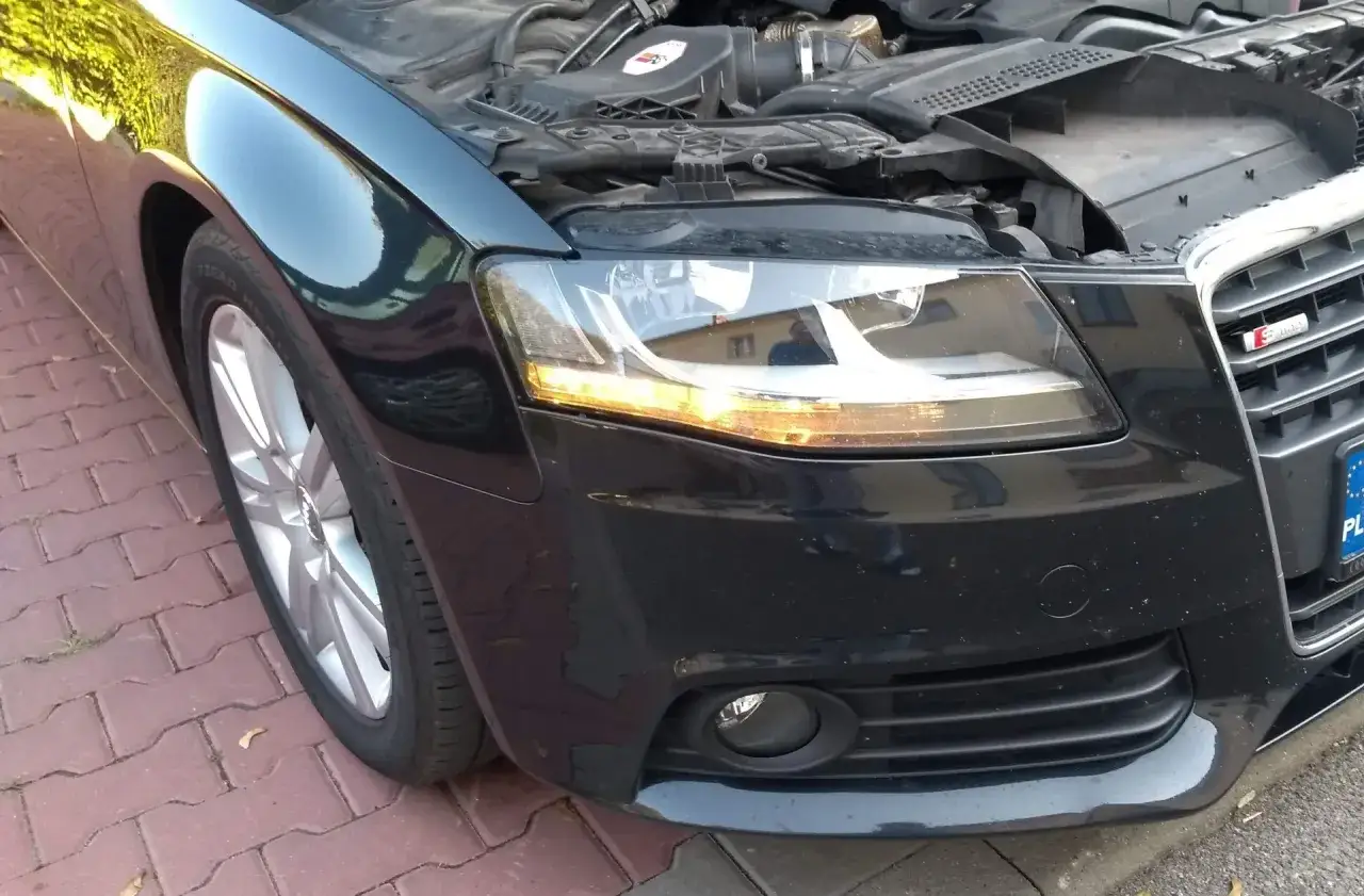 Audi A4 B8 przód: wymiana żarówki kierunkowskazu. Widok na reflektor i fragment maski.