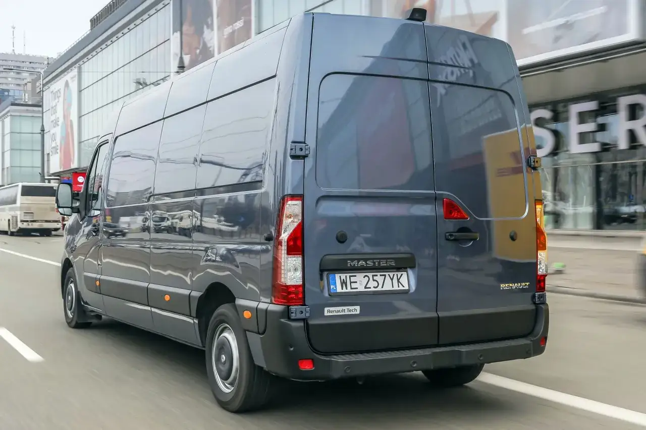 Szary Renault Master 3 w ruchu miejskim. Wymiana żarówki H7 w tym modelu może być wyzwaniem, ale warto dla bezpieczeństwa.