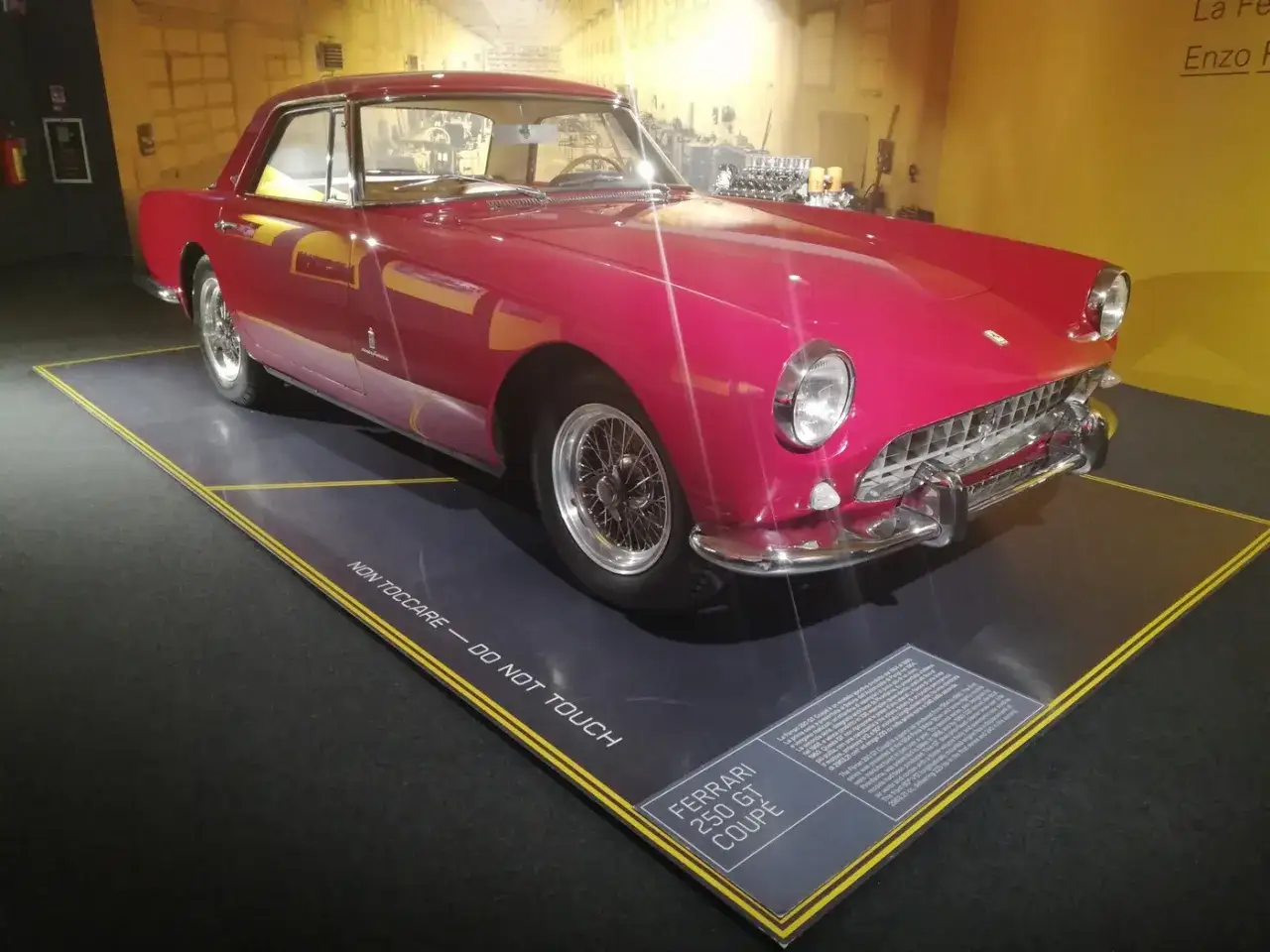 R&oacute;żowy Ferrari 250 GT Coupe, dzieło Enzo Ferrari, lśni w muzeum. Klasyk z lat 60. na wystawie.