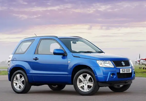 Niebieski Suzuki Grand Vitara 2005 na tle nieba z chmurami i samolotem.